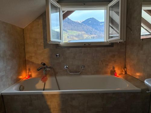 a bathroom with a tub with a window and candles at International Family Guesthouse in Schüpfheim