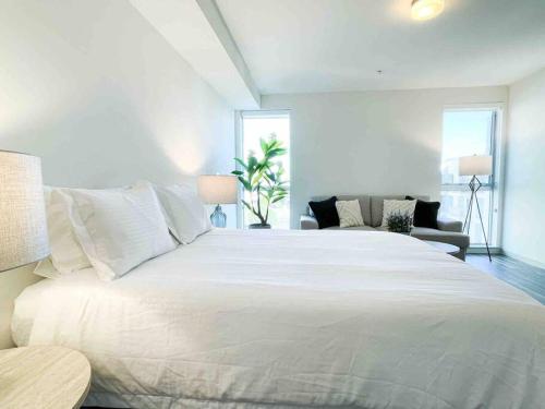 a bedroom with a large white bed and a couch at Studio Downtown Walk to Convention Center in Los Angeles