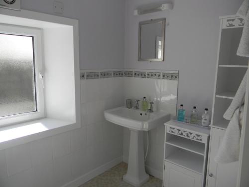 a white bathroom with a sink and a mirror at Harbour Lights Guesthouse in Stranraer