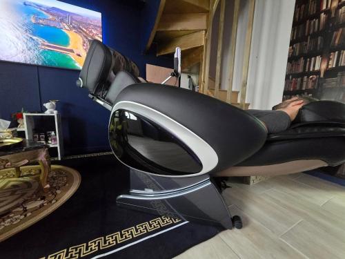 a person laying on a chair in a room at Maison équipée avec petit déjeuner gratuit - balnéo- sauna - siège massant et pièce secrète in Brachy
