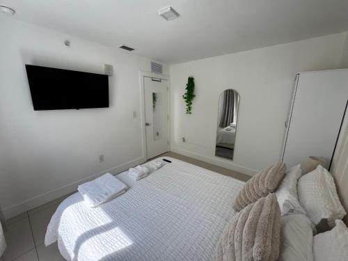 a white bedroom with a bed and a flat screen tv at Modern Bedroom In Central Miami in Miami