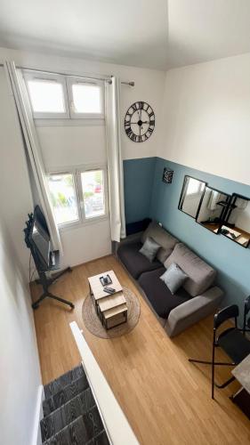 un salon avec un canapé et une horloge au mur dans l'établissement L'atelier proche Paris Marne la Vallée avec Parking Gratuit, à Bussy-Saint-Georges