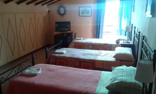 a room with three beds and a television in it at La Palazzina in Chiusdino