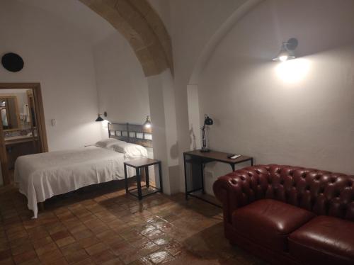 a bedroom with a bed and a leather couch at Agli Archi Dimore Storiche in Matera