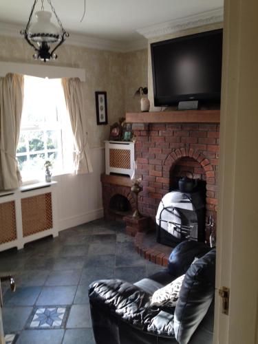 a living room with a brick fireplace with a tv at Riverside Lodge in Carlingford