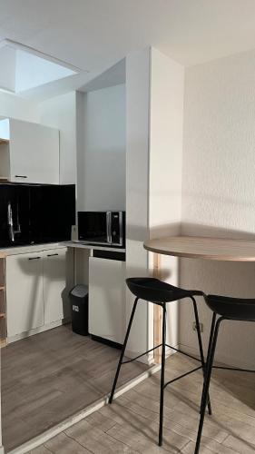 une cuisine avec des armoires blanches et une table et des chaises dans l'établissement Appartement centre de Bordeaux, à Bordeaux