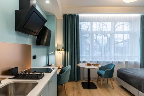 グディニャにあるSQUARE APARTMENTS GDYNIAのベッド、キッチン、テーブルが備わる小さな客室です。