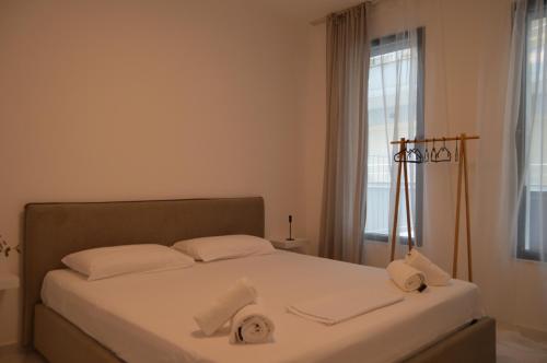 a bedroom with a bed with white sheets and a window at Luis Luxury Apartment in Sarandë