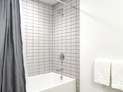 une salle de bain carrelée blanche avec une baignoire et une douche dans l'établissement Suite Downtown Pool and Gym Access, à Los Angeles