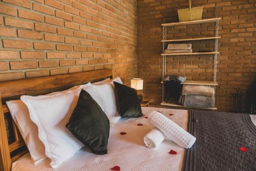 a bedroom with a bed with a brick wall at Chalé pinheirinho in Itamonte