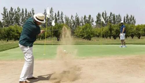 two men playing golf on a golf course at Villa Atlas piscine privée sans vis à vis AGADIR in Riaïna