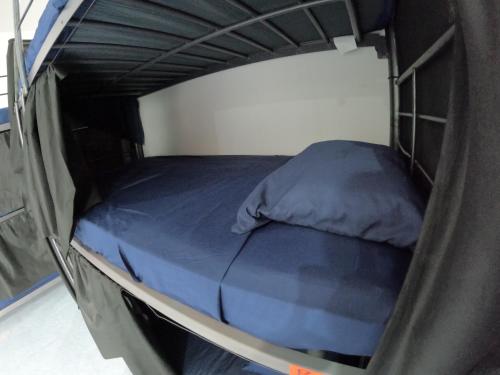 a small bed in a black bunk bed room at Casamaya Hostel & Diving in Cozumel