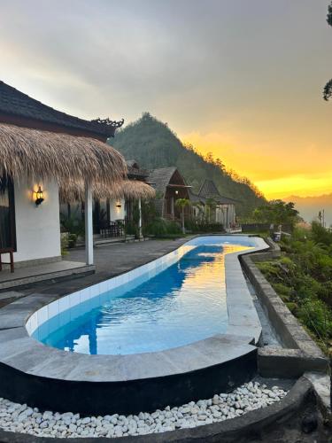 a pool at a resort with a sunset in the background at Batur cottage in Kubupenlokan