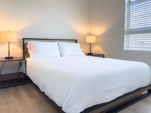 a large white bed in a bedroom with two lamps at Studio Suite - 5 Min Walk to Crypto Arena and Convention Center in Los Angeles