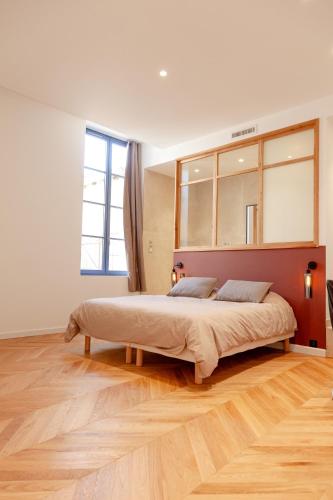une chambre avec un grand lit et un parquet dans l'établissement Douceur Nîmoise, à Nîmes