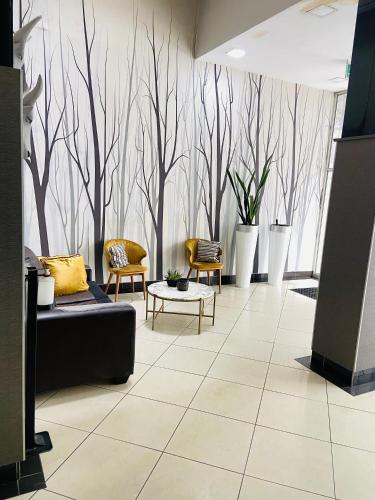 a lobby with a couch and chairs and trees on the wall at The Orange Corner in Johannesburg