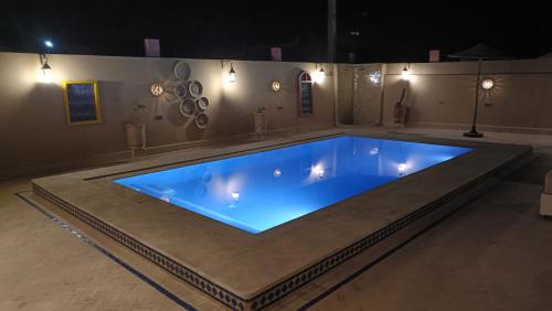 a large swimming pool with blue water in a room at Riad Dar Poublanc in Merzouga