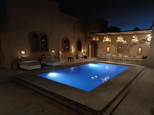 a swimming pool in the middle of a yard at night at Riad Dar Poublanc in Merzouga