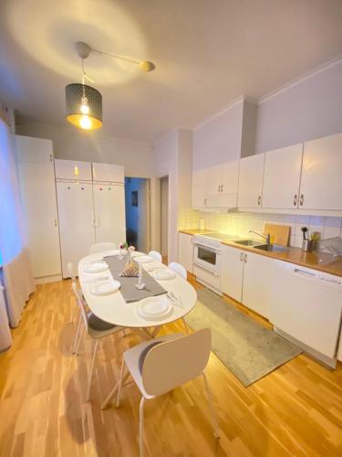 a kitchen with white cabinets and a table and chairs at Noah Longstay Nygatan 36 in Skellefteå