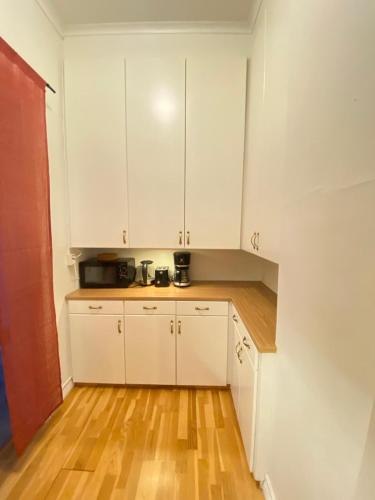 a kitchen with white cabinets and a wooden floor at Noah Longstay Nygatan 36 in Skellefteå
