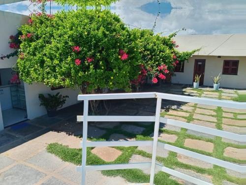 a white bench in front of a house with flowers at Pousada Canto do Mar Luís Correia in Luis Correia
