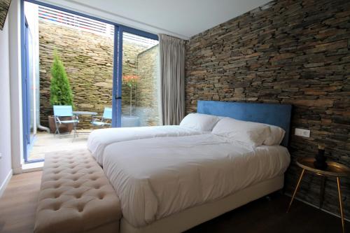 a bedroom with a large bed and a brick wall at Hotel Apartamentos Casas da Fortaleza in Lugo