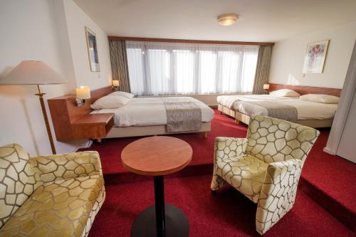 a hotel room with two beds and a table and chairs at Hotel Restaurant in den Hoof in Maastricht