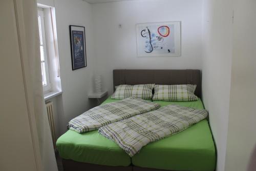 ein Bett mit grüner Bettwäsche und Kissen in einem Schlafzimmer in der Unterkunft Berghaus Feldberg "Titiseeblick" in Bärental in Feldberg