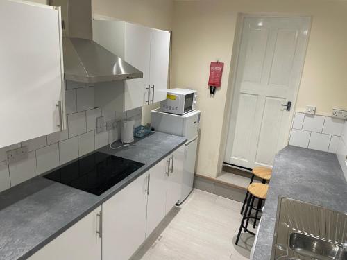 a small kitchen with white cabinets and a microwave at Roseville in Sunderland