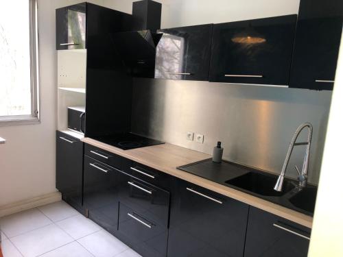 - une cuisine avec des placards noirs et un évier dans l'établissement Superbe T3 calme proche de Lille - La Madeleine, à La Madeleine