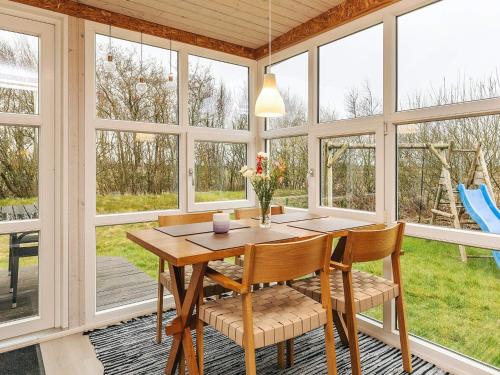 a dining room with a table and chairs and windows at Tranquil Nature Escape-By Traum in Thyholm