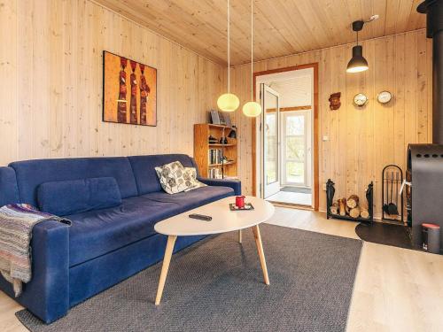 a living room with a blue couch and a table at Tranquil Nature Escape-By Traum in Thyholm