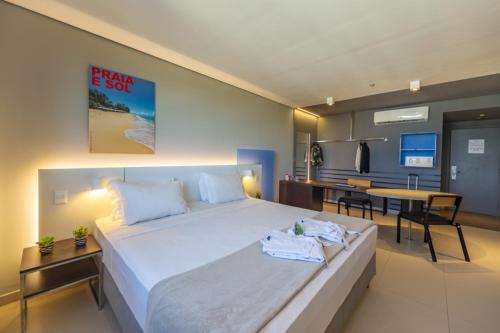 a bedroom with a large bed and a dining room at Intercity Salvador in Salvador