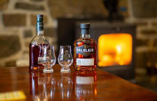 two bottles of whiskey and two glasses on a table at Eddrachilles Hotel in Scourie