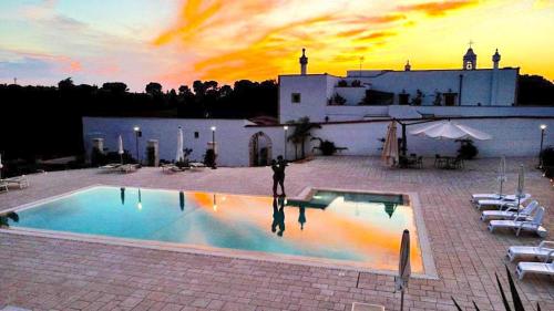 a person standing next to a swimming pool at sunset at Masseria Del Crocifisso in Polignano a Mare