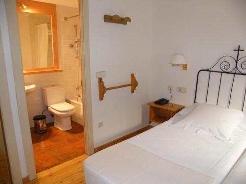 a bedroom with a bed and a bathroom with a toilet at Hotel de La Font Peralada in Peralada