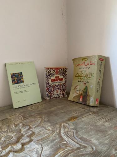 three books sitting on top of a wooden table at House of Sun guesthouse in Tamraght Ouzdar