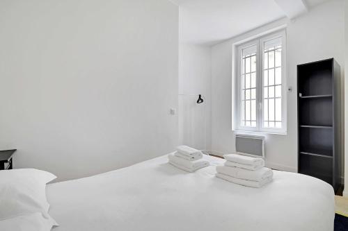 - une chambre blanche avec un grand lit blanc et des serviettes dans l'établissement Comfortable apt - 1BD - 4P - Montmartre, à Paris