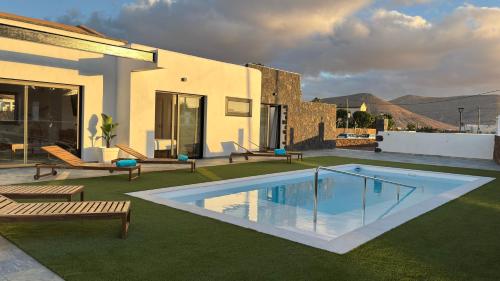 Un patio trasero con piscina y una casa. en Casa El Cachorro, en La Oliva