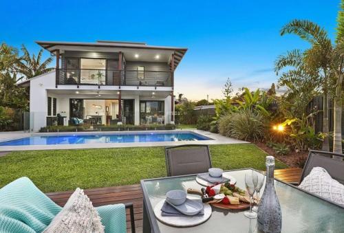 a villa with a swimming pool and a table with food at WATERFRONT HOME BORDERING MOOLOOLABA in Buddina