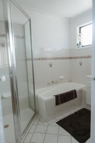 a white bathroom with a tub and a shower at Sunny Dayz Shellharbour in Barrack Point