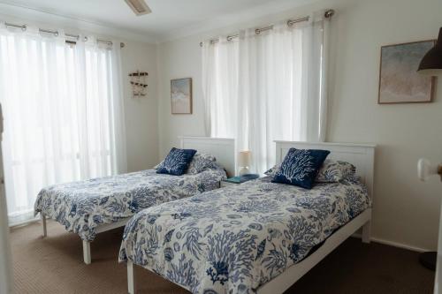 a bedroom with two beds with blue and white sheets at Sunny Dayz Shellharbour in Barrack Point
