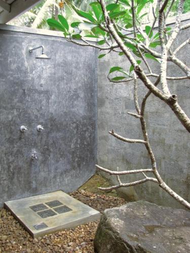 a shower with a door next to a tree at Halketha in Matugama