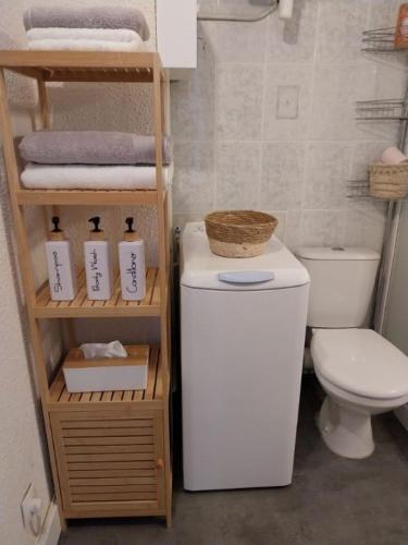 La salle de bains est pourvue de toilettes et d'une étagère avec des serviettes. dans l'établissement Le Quai401 YourHostHelper, à Gruissan