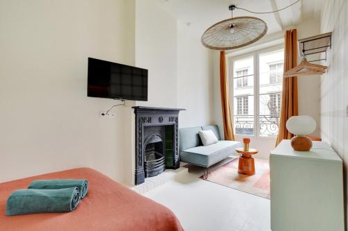 un salon avec une télévision et une cheminée dans l'établissement La Petite Maison du Marais avec Sauna, à Paris