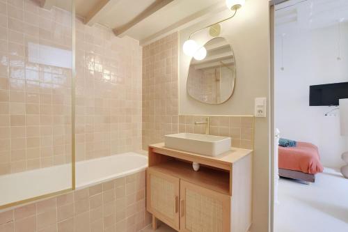 une salle de bain avec un lavabo, une baignoire et un miroir dans l'établissement La Petite Maison du Marais avec Sauna, à Paris