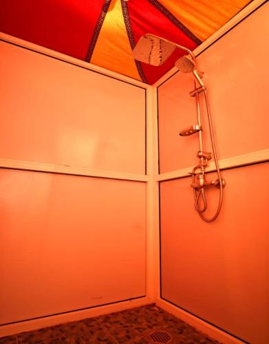a shower in a bathroom with a wall at Merzouga Beduien Camping in Merzouga