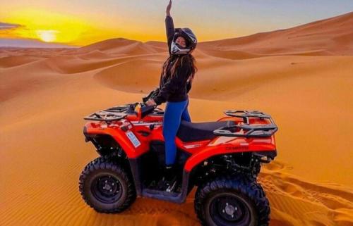 a woman riding a quad bike in the desert at Desert Berber Fire Camp in Merzouga