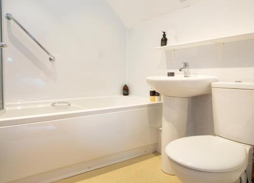 a white bathroom with a toilet and a sink at Eddrachilles Hotel in Scourie