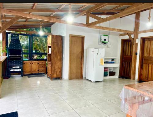 a kitchen with a white refrigerator and wooden ceilings at Quarto Recanto Monte Trigo in São Francisco do Sul